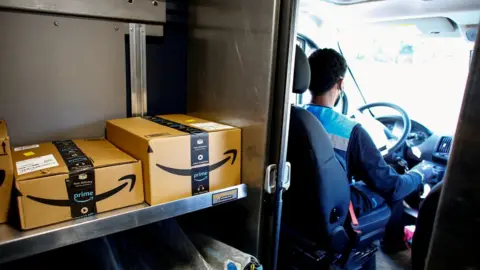 Reuters driver in mask with Amazon boxes