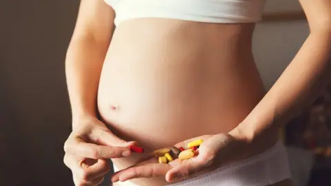 Getty Images Pregnant stomach with vitamin pills