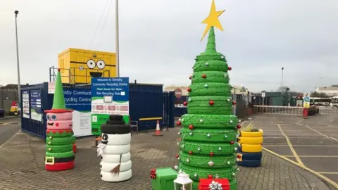North East Lincolnshire Council Discarded tyres stacked up on top of each other and painted to look like a Christmas tree, snowman and elf