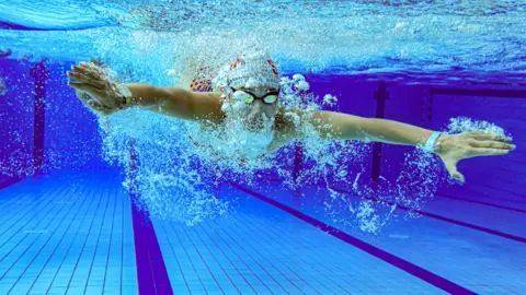 Getty Images A person swimming under water in a swimming pool