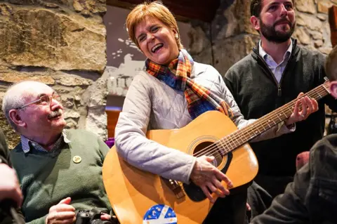 Jeff J Mitchell / Getty Images Nicola Sturgeon strums a guitar
