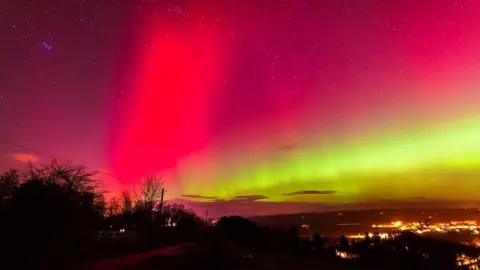 The Aurora Borealis seen in pink and orange over a British landscape
