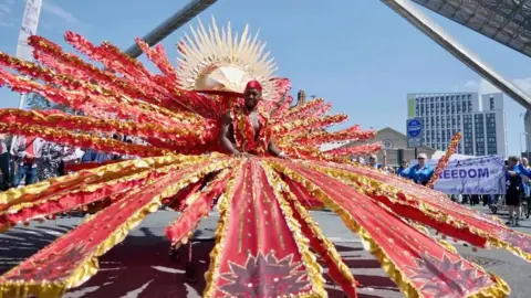 BBC Carnival parade showing man with red costume