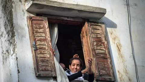 AFP People look out of a window in Rabat, Morocco - Friday 27 March 2020