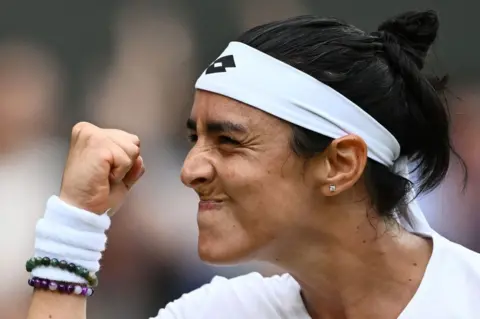 Hannah Mckay/Reuters Ons Jabeur smiles and clenches her fist in celebration.