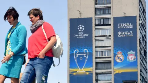 Getty Images Women walk past a poster of the 2018 UEFA Champions League Final set on a building in Kiev
