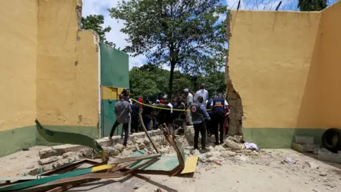 Reuters People stand outside the main door of Kuje Medium prison on 6 July after it was destroyed during the attack