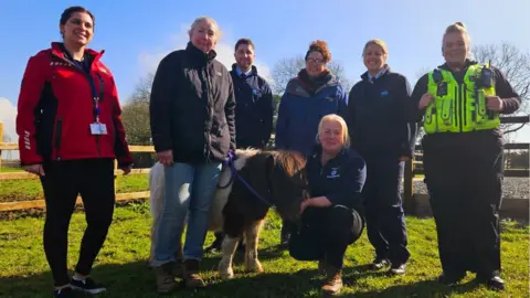 Chippenham Police Maisie the Shetland pony and her owner reunited in a field, alongside friends and police officer in uniform