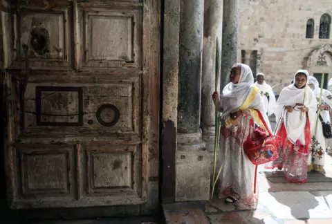 EPA Women dressed in white robes enter the Church.