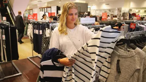 Getty Images A woman looks at a jumper for sale in a David Jones department store in Sydney