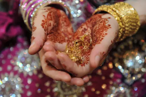 Alamy Bride holds wedding rings - Asian wedding, Bradford