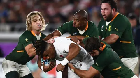 Getty Images England's wing Anthony Watson (C) is tackled during the Japan 2019 Rugby World Cup final match between England and South Africa at the International Stadium Yokohama in Yokohama on November 2, 2019.
