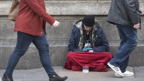 A homeless man begging outside Victoria Station