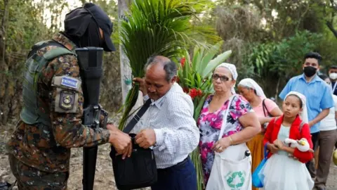 Reuters A soldier searches people at a checkpoint in El Salvador, April 4, 2022.