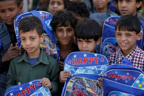 Khaled Abdullah/ Reuters Orphan students carry bags they received from a local charity organisation