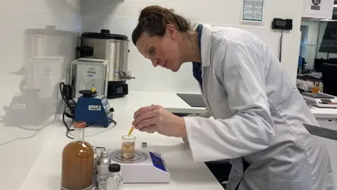 BBC/Jess Warren Vanessa Jacoby drops liquid into a beaker with a pipette