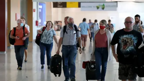 Getty Images Passengers wearing masks walk through Adelaide Airport