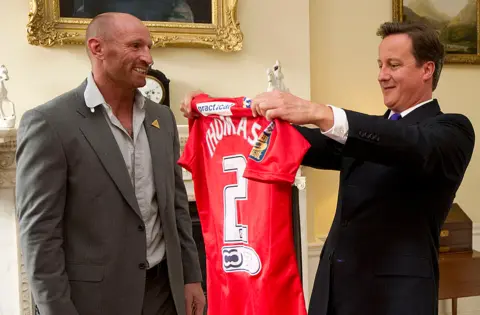 CARL COURT/Getty Images Presenting a shirt to then Prime Minister David Cameron in 2011 at a meeting of sports figures to discuss homophobia and transphobia in sport