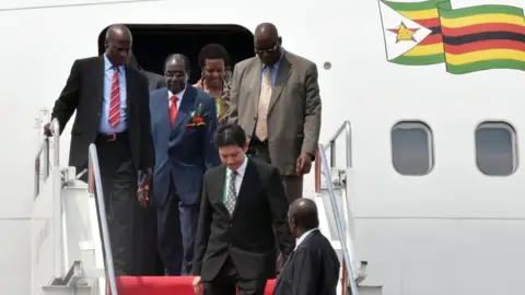 AFP Zimbabwe's President Robert Mugabe (second on the left) disembarks from an aircraft after arriving at Halim airport in Jakarta (21 April 2015)
