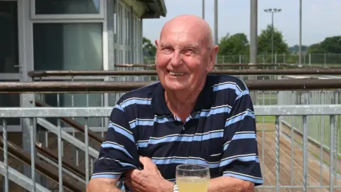 Ray Grocott smiling at the camera in a striped t shirt