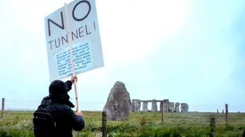 Getty Images Man holds sign reading "No Tunnel"