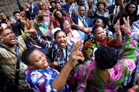 Reuters People wave and shout in joy.