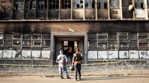 A police officer and security guard stand in front of the gutted 80 Albert Street building