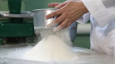 Getty Images A man sifting flour onto a table