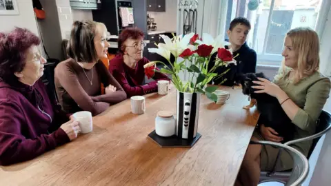 Helen, Hannah, Iren, Taras and Nataliya sit together around a table chatting