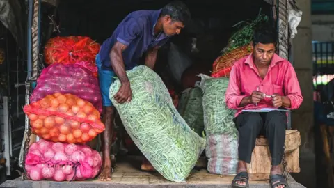 Getty Images A labourer carries a sack of green beans at a market in Colombo.