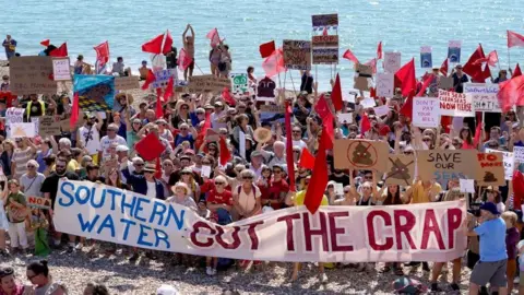 PA Media Protesters on a beach in St Leonards, Sussex, demonstrate against the release of raw sewage into the sea