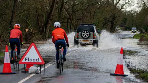 PA Media A vehicle is driven through floodwater at Apperley, Gloucestershire, where the River Severn burst it's banks and has flooded fields and roads across the county.