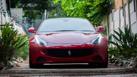 Shiraaz Mohamed/BBC A Ferrari F151 drives off from the Blackhead Consulting offices in Bryanston, Johannesburg, 6 October 2020, after seized by Assets Forfeiture Unit (AFU)