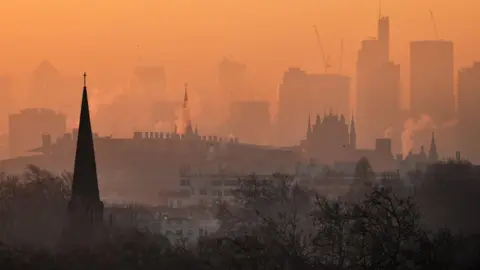 Dawn from Primrose Hill looking towards the City with chimneys billowing