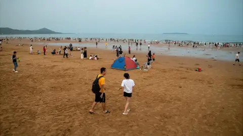 Joyce Liu/BBC Tourists at a beach in China