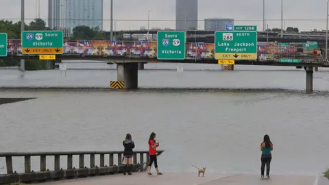 Getty Images Image shows flood waters on a highway in Houston almost reaching the signs above.