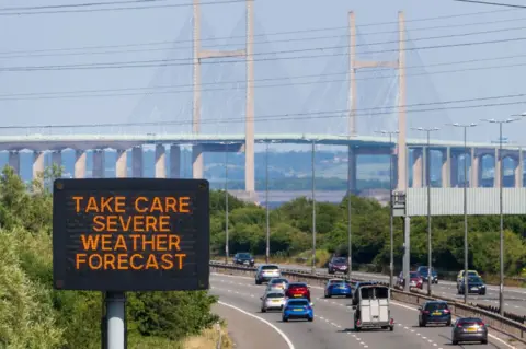 Heat warning matrix sign with the Severn Bridge in the background