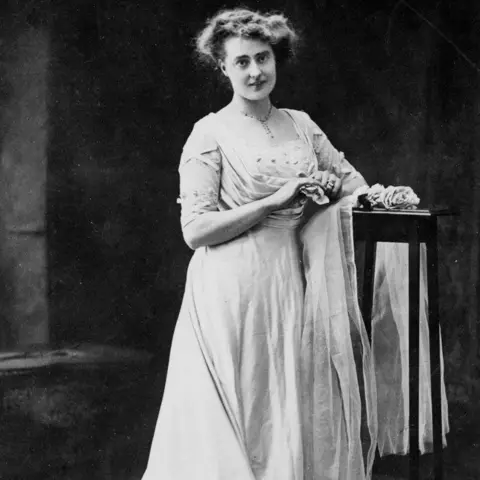 National Motor Museum Trust A black and white image of Eleanor Velasco Thornton. She is wearing a white draped dress and a necklace