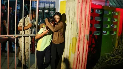 Reuters Two females hug as they leave the school where a siege happened 