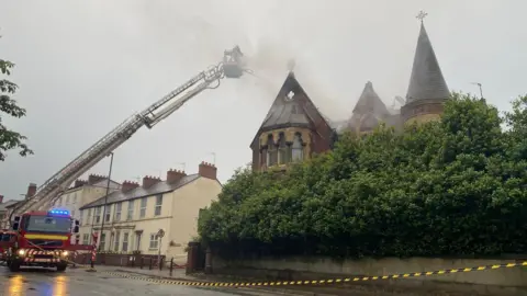Aerial ladder platform and police cordon at smoking building