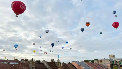 James Bennetts Many hot air balloons pictured in the sky above houses