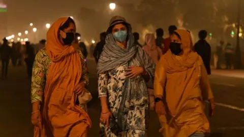 Visitors wear masks as they walk in front of India Gate in Delhi