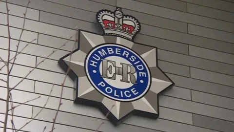 The Humberside Police badge on the side of a silver-clad wall.