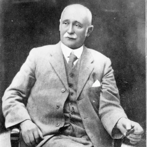 Gainsborough Heritage Association A black-and-white photo of an elderly man with short white hair and a moustache. He is sitting in a chair and wearing a three-piece suit, white shirt and tie.