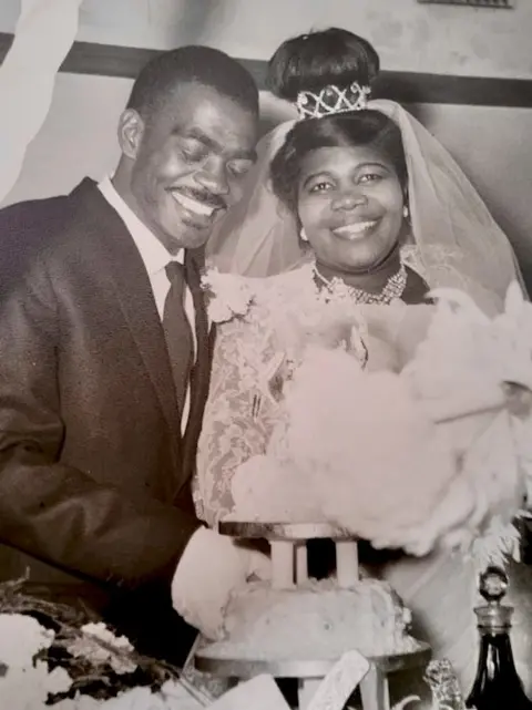 Steve Reeves A black and white picture of a couple on their wedding day, smiling as they cut the cake
