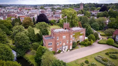 An aerial image of the Hertford Castle grounds. The brick gatehouse is surrounded by trees and the River Lea