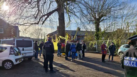 James Fell/BBC Police officers engaging with campaigners at the oak tree, which is situated in a car park and covered in yellow ribbons.