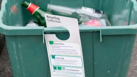 West Berkshire Council Information tag hangs from green box with glass bottles inside
