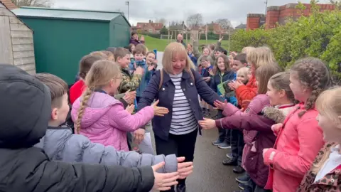 A woman receiving a guard of honour from school children