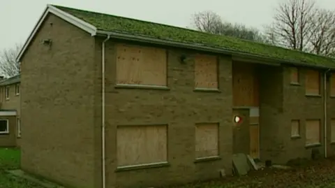 An abandoned 1960s building with boarded-up windows